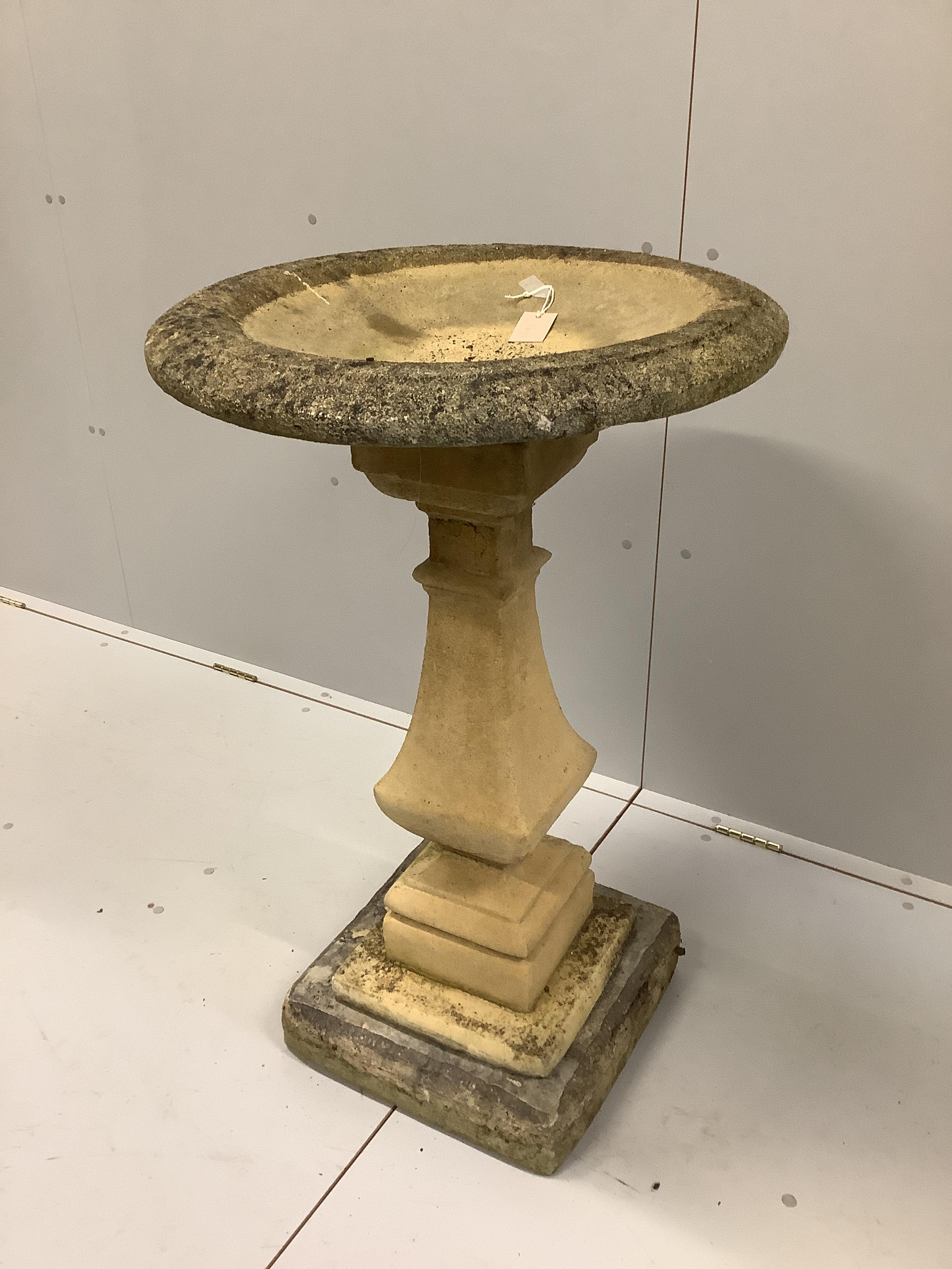 A circular stone bird bath on square plinth, diameter 58cm, height 95cm.